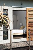 View into bedroom from wooden terrace through open sliding shutters