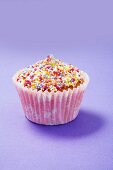 A cupcake decorated with colourful sugar sprinkles