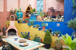 Original courtyard with colourful steps, potted plants, garden table with chairs and chimney grill