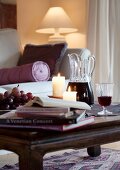 Bücher, Weintrauben, Kerze und Rotwein auf einem Couchtisch