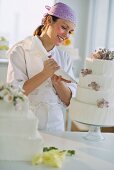 Happy young woman decorating wedding cake