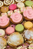 Rows of cupcakes, scones, macarons, Swiss rolls and pieces of mini Battenburg cake