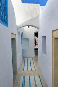 Narrow, winding corridor with woven rugs in North African building