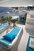 Sun loungers with blue blankets on roof terrace and view of typical, North-African architecture