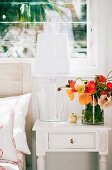 Sommerblumenstrauss in Glasvase auf weißem Vintage Nachttisch