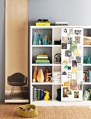 Shelving unit with single sliding door covered with pictures; photo of classic chair on long roll of paper decorating wall