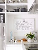 Zeichnung an der Wand in weisser Einbauküche mit Edelstahlkochgeschirr