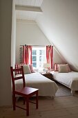 Small, plain white guest bedroom with red accents in attic