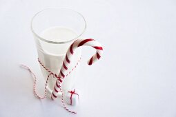 Ein Glas Milch mit Zuckerstange, daneben Päckchen