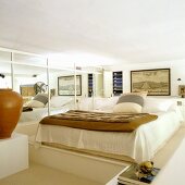 In Naturtönen gestaltetes Schlafzimmer mit Doppelbett auf Podest vor einer Spiegelfront