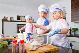 Germany, Girls and boy sifting flour in bowl