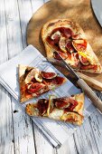 A long thin pizza topped with ham and figs