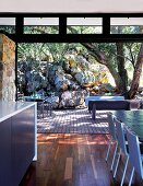 Sliding doors without threshold between dining area and wooden terrace; outdoor seating area sheltered by boulders