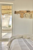 Ferienstimmung in hellem Schlafzimmer mit Blick auf die in der Meeresbrise wehenden Vorhänge der Veranda