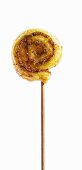A wooden skewer topped with a puff pastry whirl with pesto