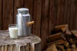 A milk churn and a milk glass on a rustic wooden block