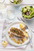 Coalfish fillet with a herb crust and grilled gooseberries on a plate