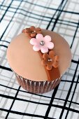 A chocolate cupcake with caramel filling, topped with fondant icing