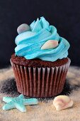 A chocolate cupcake with salted caramel and marine life decorations