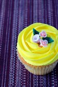 A lemon cupcake with sugar flowers