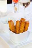 Polenta Fries Standing in a White Dish with a Dish of Dipping Sauce; White Wine