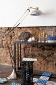 Ornaments on console table, stainless steel standard lamp, basketwork side table and Dutch-style floor tiles