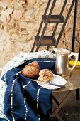 Blue and white patterned tablecloths, silver pitcher and Dutch plate of bread on metal table