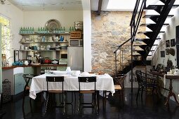 Küche mit unverputzter Steinmauer, Innentreppe, Kochnische und Esstisch