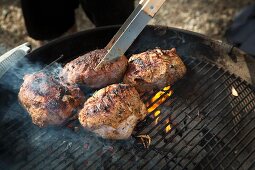 Mariniertes Lammfleisch auf dem Holzkohlengrill wenden