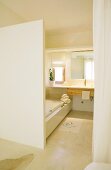 View of continuous washstand counter with wooden drawers and fitted bathtub to one side in simple ensuite bathroom