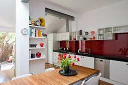 Bouquet of tulips on dining table in modern kitchen with long kitchen counter and red glass splashback