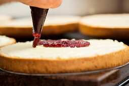 A sponge cake being spread with jam