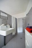 Ensuite bathroom clad in grey mosaic tiles with open shower and industrial-style sink