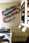 Two armchairs with traditional floral upholstery below fitted shelving in niches and modern, 'bookworm' bookshelf on wall in background