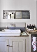 Collection of mirrors in niche above vintage sink on grey base unit in simple interior