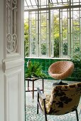 Two comfortable chairs and table in classic conservatory with green wall tiles and mosaic floor