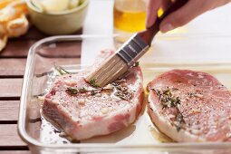 Pork chops being brushed with barbecue marinade
