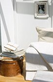 White blanket on sofa next to stack of books on round vintage storage box on floor