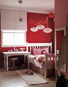 Red and white girl's bedroom - red and white lanterns above vintage bed next to desk below window with half-open blind