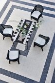 Wicker chairs around a mosaic table and black and white tile patterns (top view)