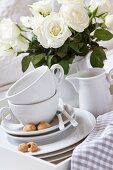 White porcelain crockery and a bunch of white roses in a porcelain vase