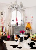 Postmodern-style child's bedroom; white plastic shell chairs on cowhide rug and neo-rococo armchair next to chest of drawers below window