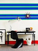 Blue and green horizontal stripes and sunburst clock above black and white work area and bright red skirting board