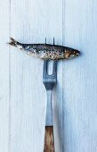 A meat fork skewering a barbecued sardine