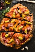 Pizza mit Pancetta, Artischocken und schwarzen Oliven, aufgeschnitten