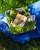 Fish terrine made from three different types of fish, on a bed of salad leaves