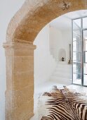 Historical, stone arched doorway and view of zebra-skin rugs
