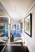 Sunny corridor with view of swimming pool; framed artworks on wall