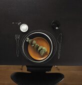 A place set at a blackboard table with a wooden plate, salt and a wine glass