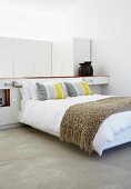 Modern double bed with throw against partition in sleeping area